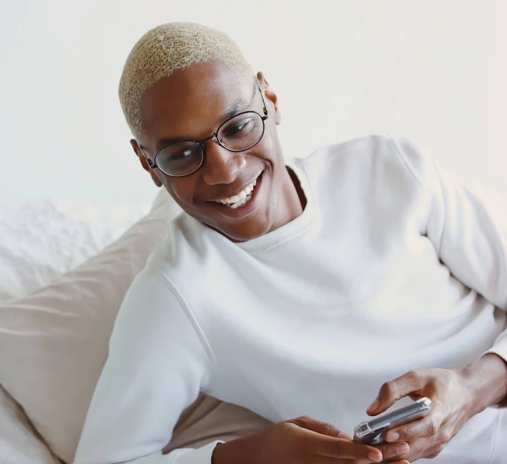 Smiling person in white shirt holding a phone